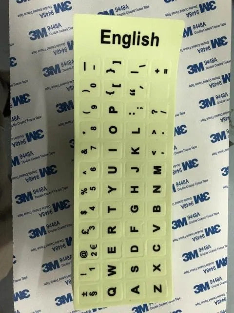 Glowing yellow multilingual keyboard stickers showing Arabic, Thai, Hebrew, French, Italian and German characters