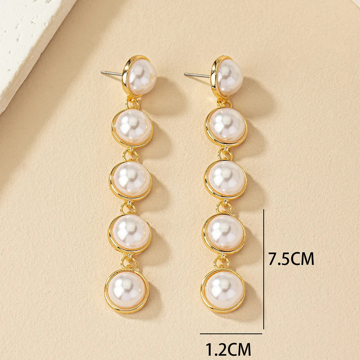 White long pearl tassel drop earrings made of electroplated metal with water flow design on white background