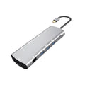 Grey aluminium USBC docking station with HDMI, VGA, USB 3.0, and charging ports on a desk.