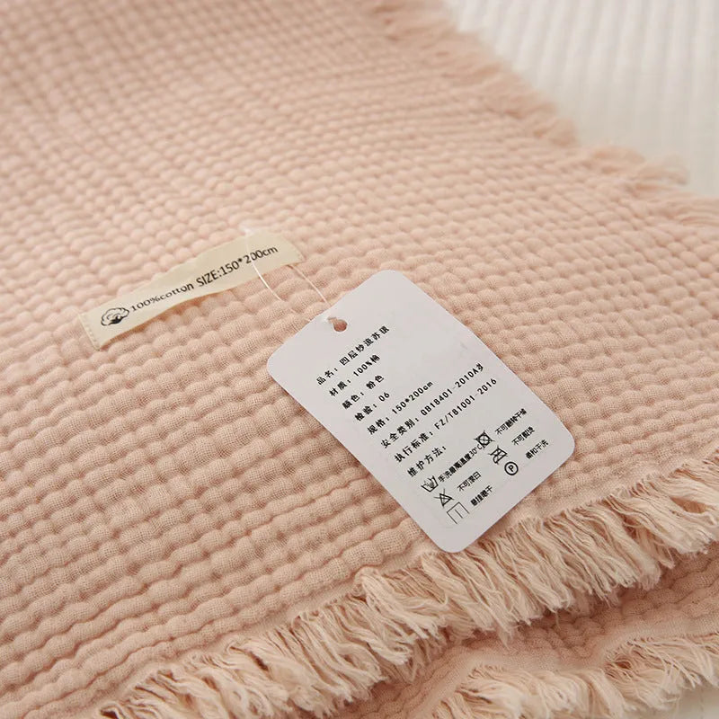 Cotton four-layer gauze blanket with tassel trim in avocado green colour, laid flat.