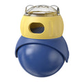 Yellow and blue plastic tumbler owl cat puzzle feeder toy on a wooden floor.