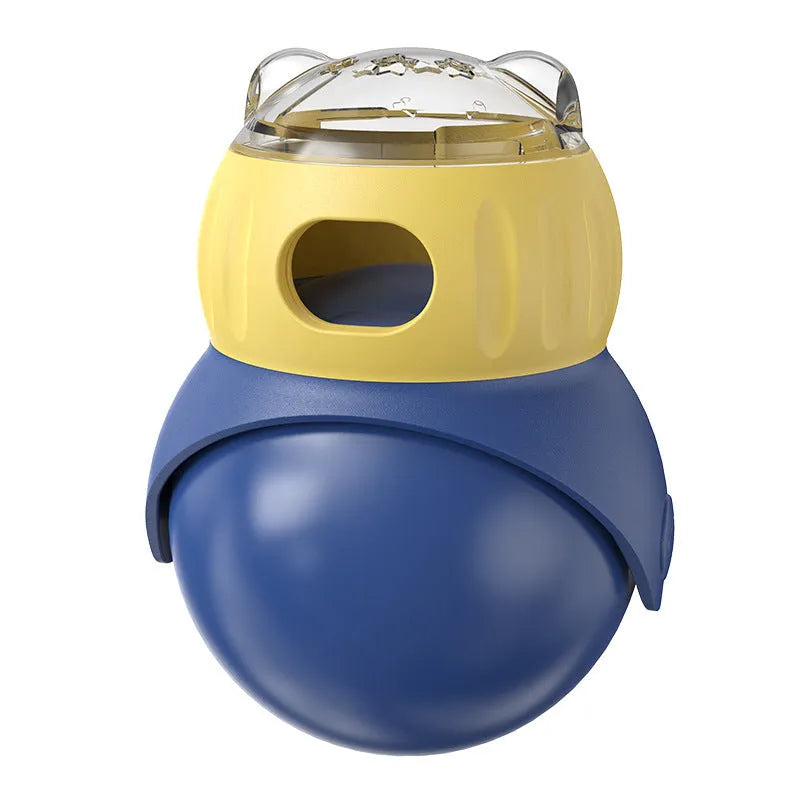 Yellow and blue plastic tumbler owl cat puzzle feeder toy on a wooden floor.