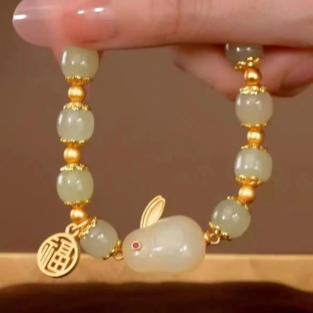Green jade hare bracelet on wrist showing fu character and lily design details.
