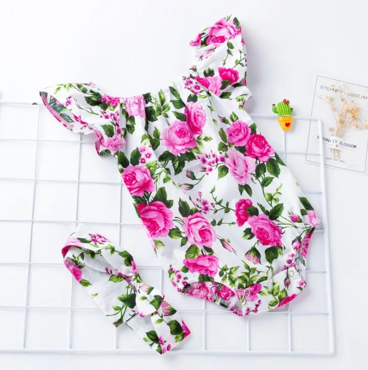 White baby girl's sleeveless cotton romper with small flying sleeves on a hanger.