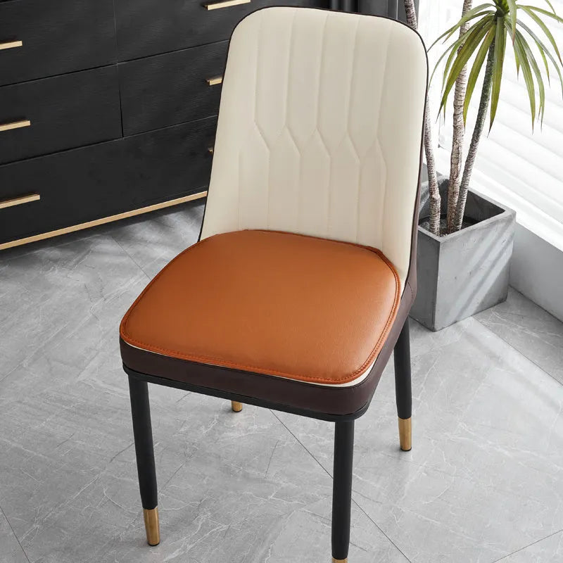 Orange horseshoe-shaped PU leather seat cushion on a wooden dining chair, showing non-slip base.
