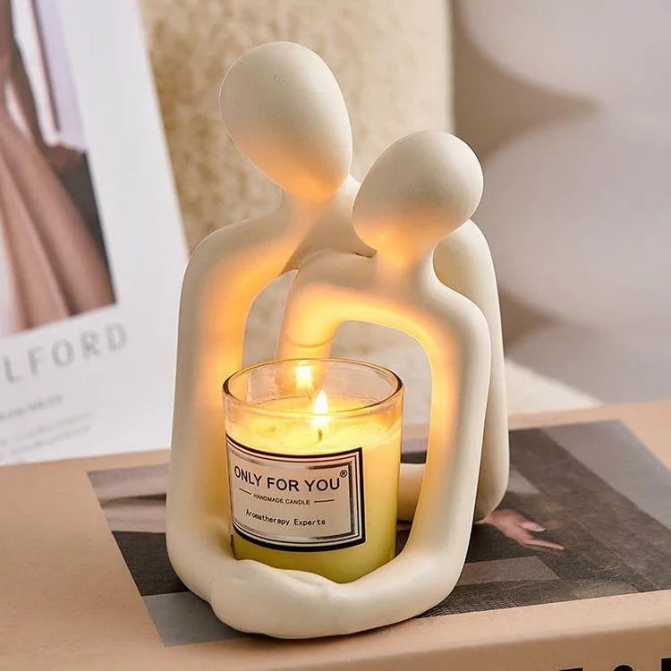 Modern loving couple resin statue in milky white or gold colour on a wooden desk.