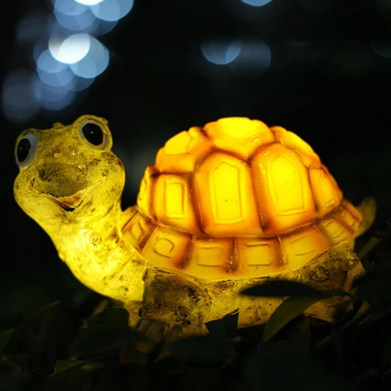 Resin solar lamp in turtle shape sitting on grass with soft LED glow at dusk