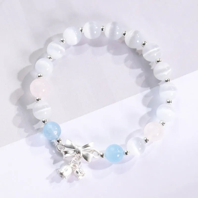 Close-up of a women's opal cat's eye stone beaded bracelet with diamond-shaped beads on a wrist.