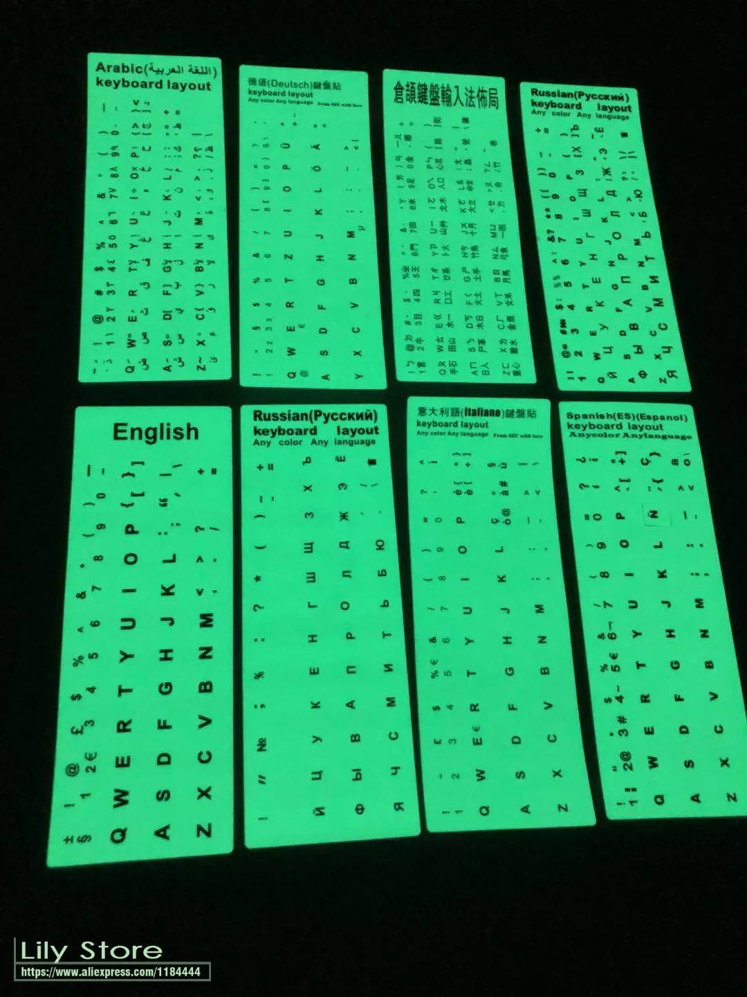 Glowing yellow multilingual keyboard stickers showing Arabic, Thai, Hebrew, French, Italian and German characters