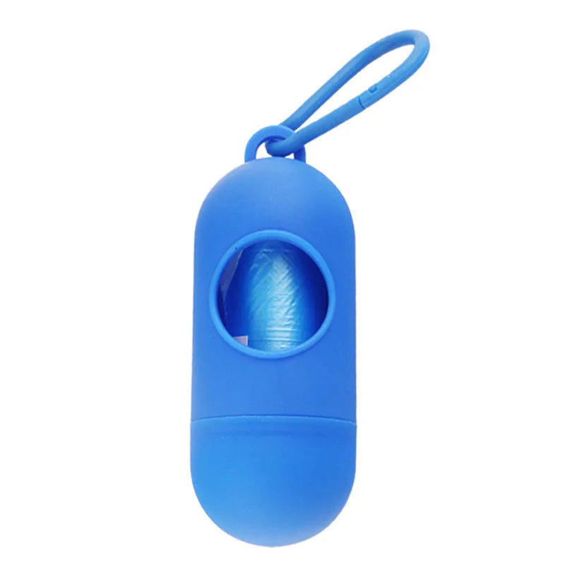 Compact black dog poop bag holder with side hook and Velcro strap, shown attached to a pair of trousers.