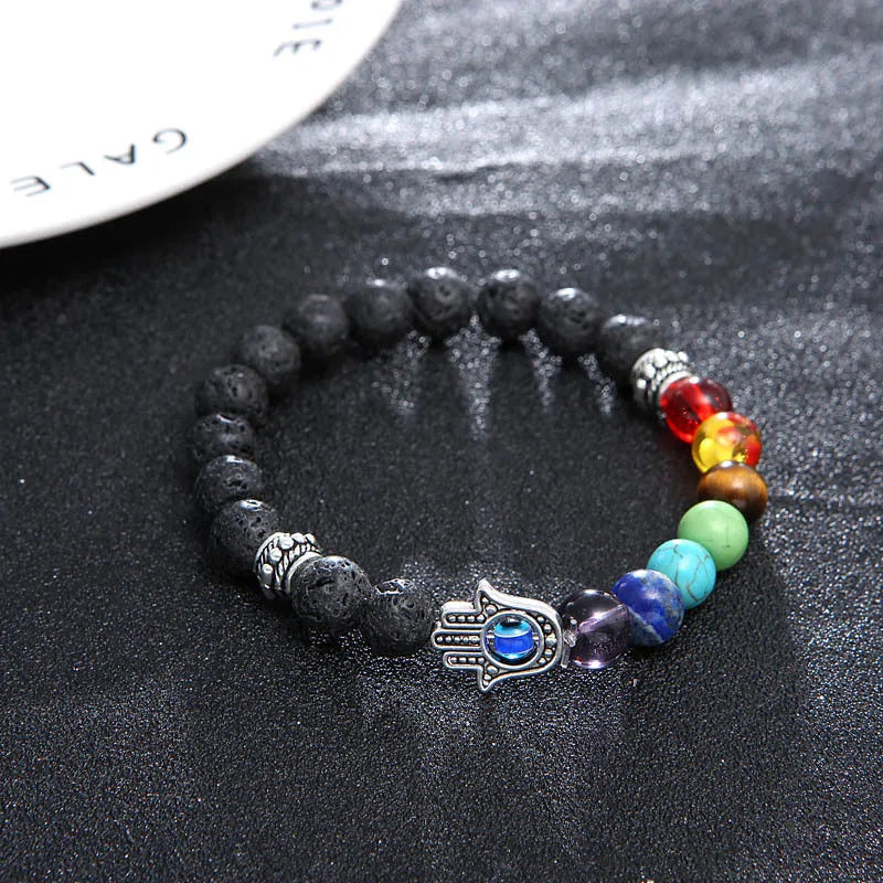 Natural volcanic rock hand chain with seven chakra stones and blue eye bead on a white background