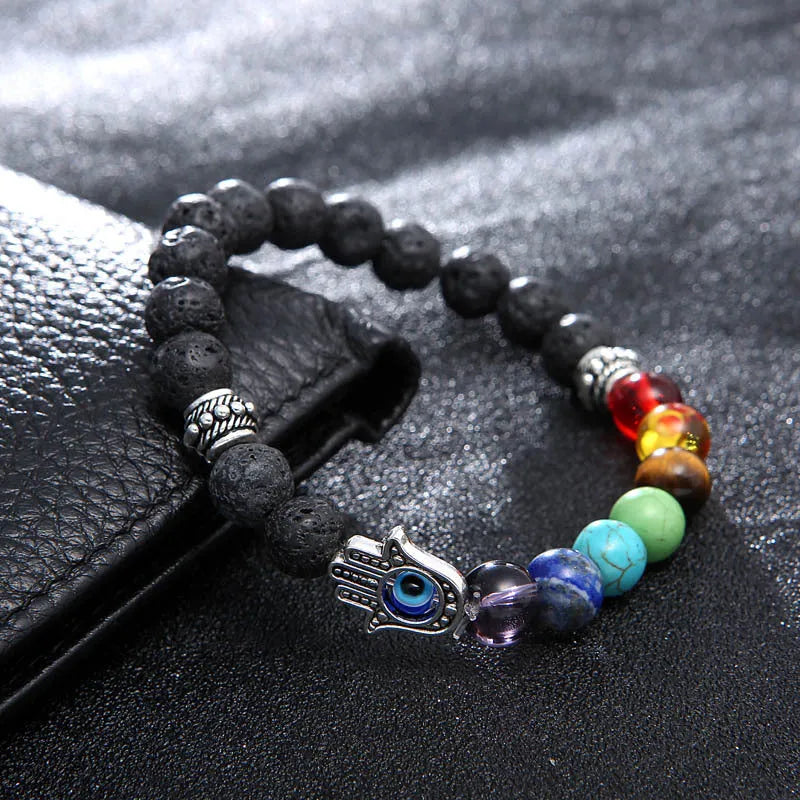 Natural volcanic rock hand chain with seven chakra stones and blue eye bead on a white background