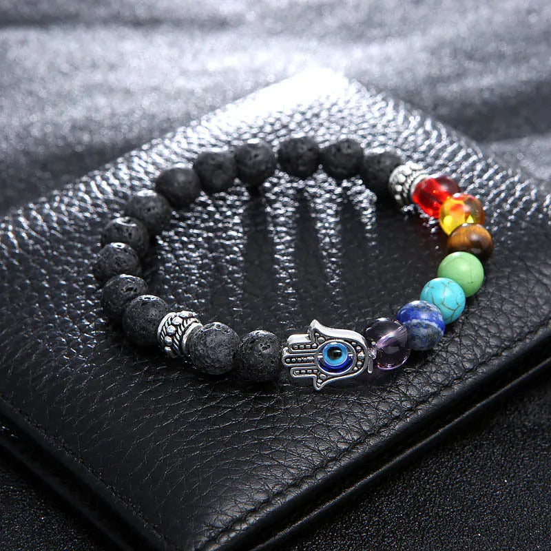 Natural volcanic rock hand chain with seven chakra stones and blue eye bead on a white background
