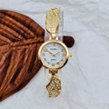 A stainless steel women's watch with a round dial on a metal strap, showing a gold-coloured face.