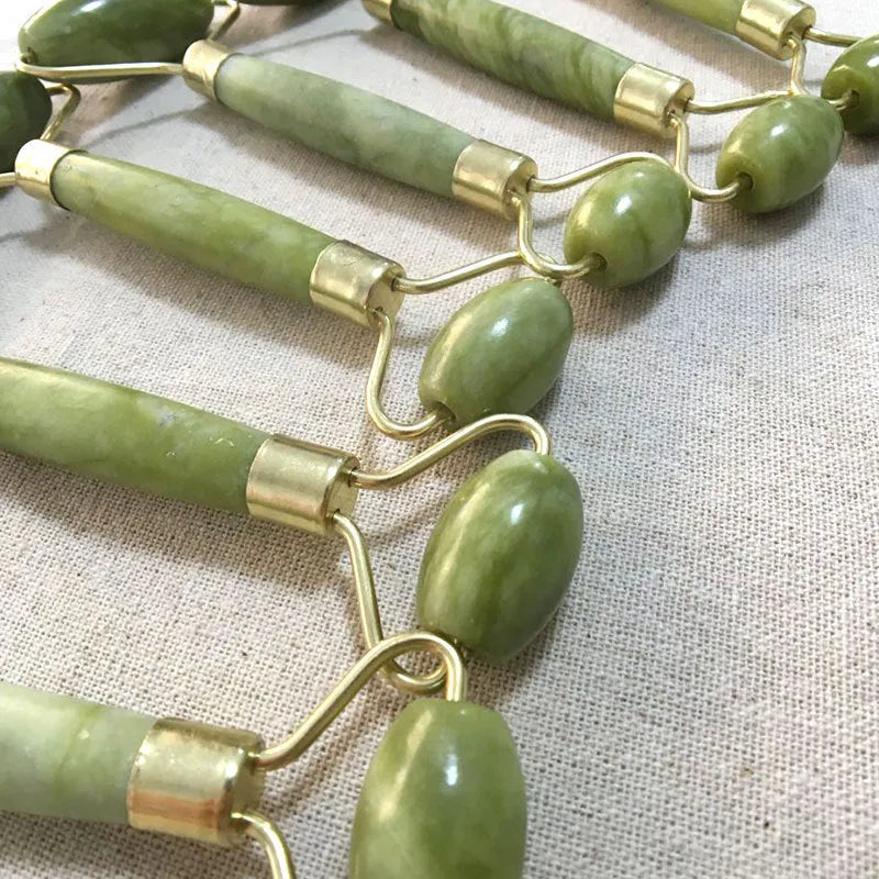 Natural Xiuyu jade double-end roller with green stone, hand-polished finish, large and small wheels on a flat surface