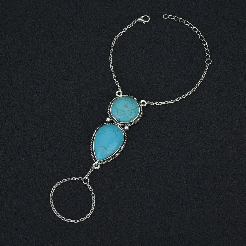Silver alloy plated drop shape bracelet with turquoise tassel on a neutral background