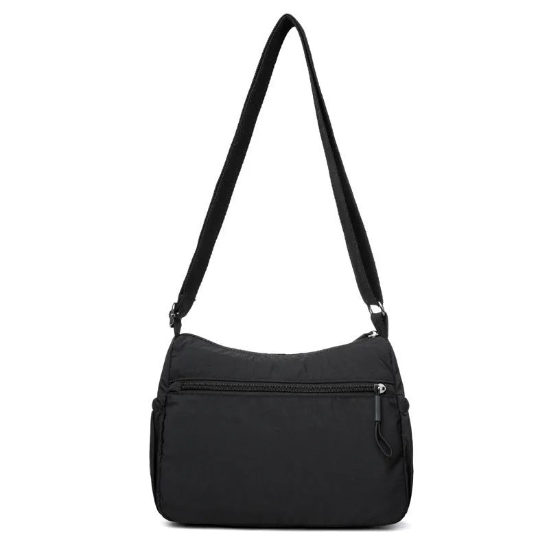 Soft nylon crossbody bag in black, grey, or red with a single shoulder strap and water-repellent finish.