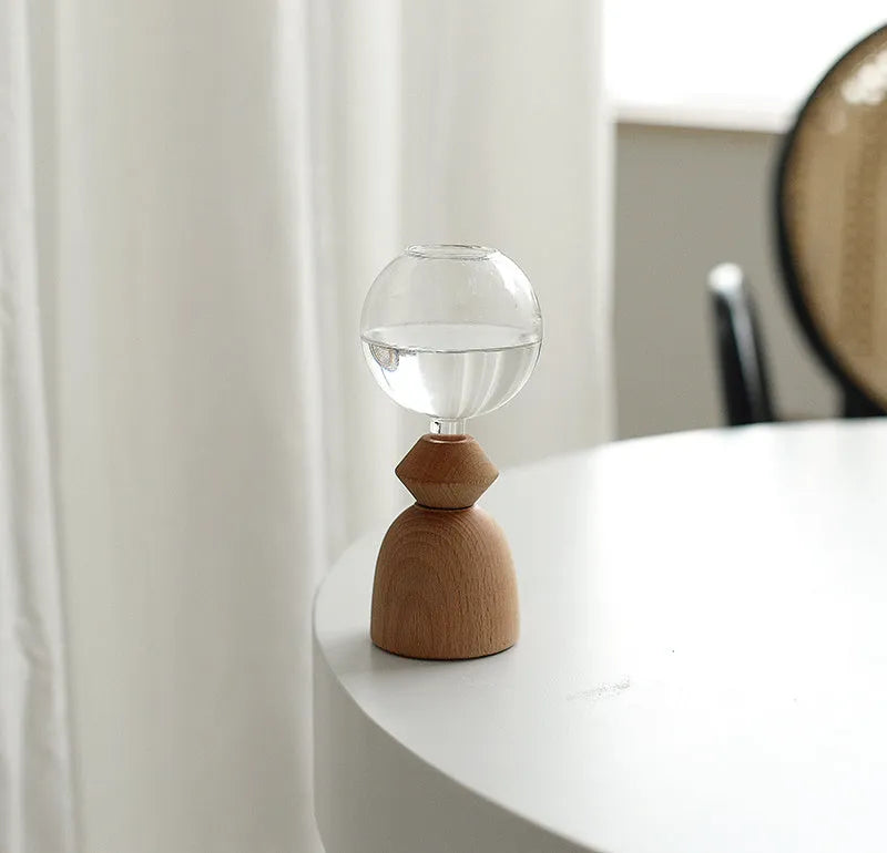 Geometric clear glass bubble vase with wooden base on tabletop with floral arrangement