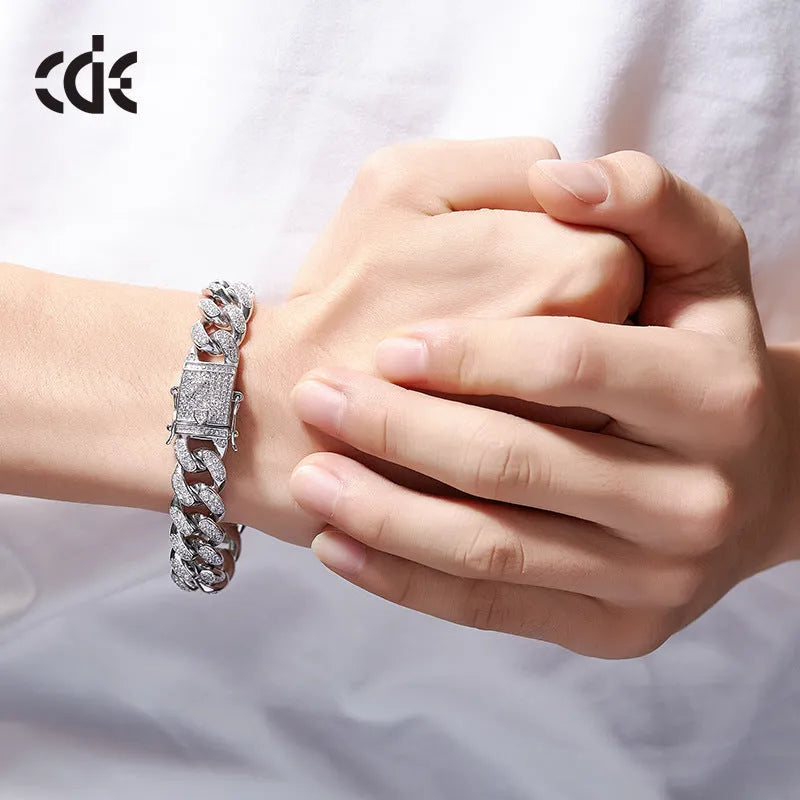 Men's gold Cuban chain bracelet with geometric alloy pendant set with a zircon stone on a neutral background