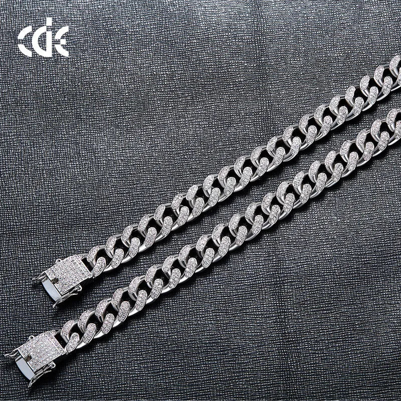 Men's gold Cuban chain bracelet with geometric alloy pendant set with a zircon stone on a neutral background