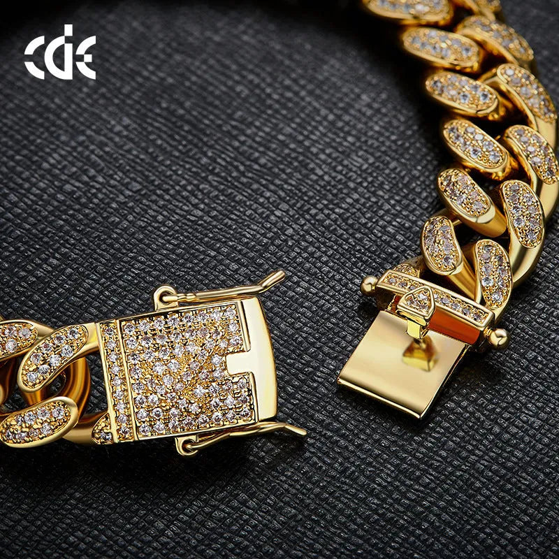 Men's gold Cuban chain bracelet with geometric alloy pendant set with a zircon stone on a neutral background