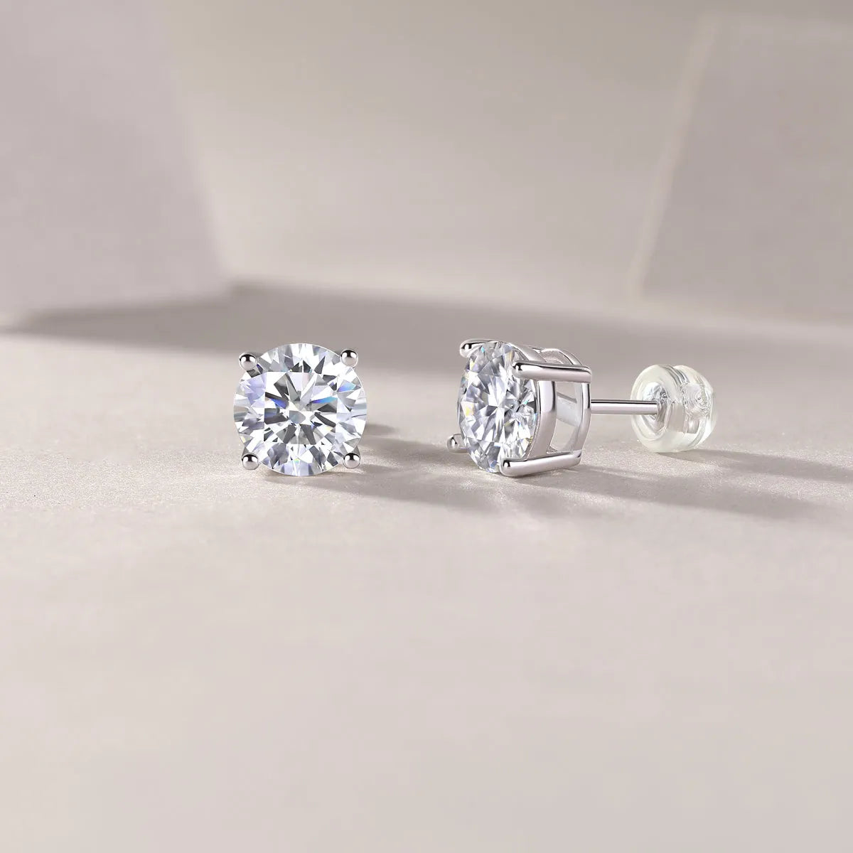 Pair of moissanite stud earrings with platinum-plated S925 silver settings, on a gift box, available in black or transparent stones