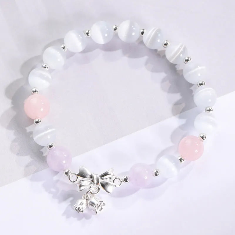 Close-up of a women's opal cat's eye stone beaded bracelet with diamond-shaped beads on a wrist.
