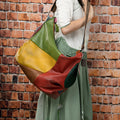 Brown cowhide leather crossbody travel bag showing main compartment open next to a 15-inch laptop and A4 magazine.