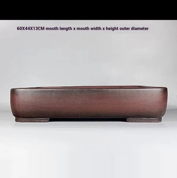 Large rectangular handmade antique purple clay flower pot on a table.