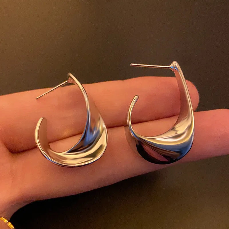 A pair of twisted geometric round metal earrings with a gold electroplated finish on a white background.