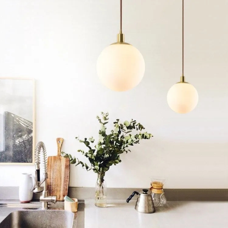 Nordic glass round spherical chandelier in milk white with copper fittings on a light background