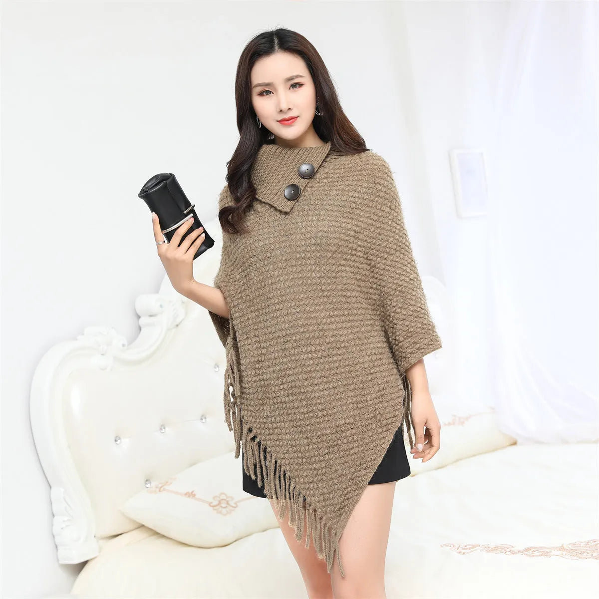 Sleeveless polka dot knit cloak in apricot colour, shown as a vest on a hanger.