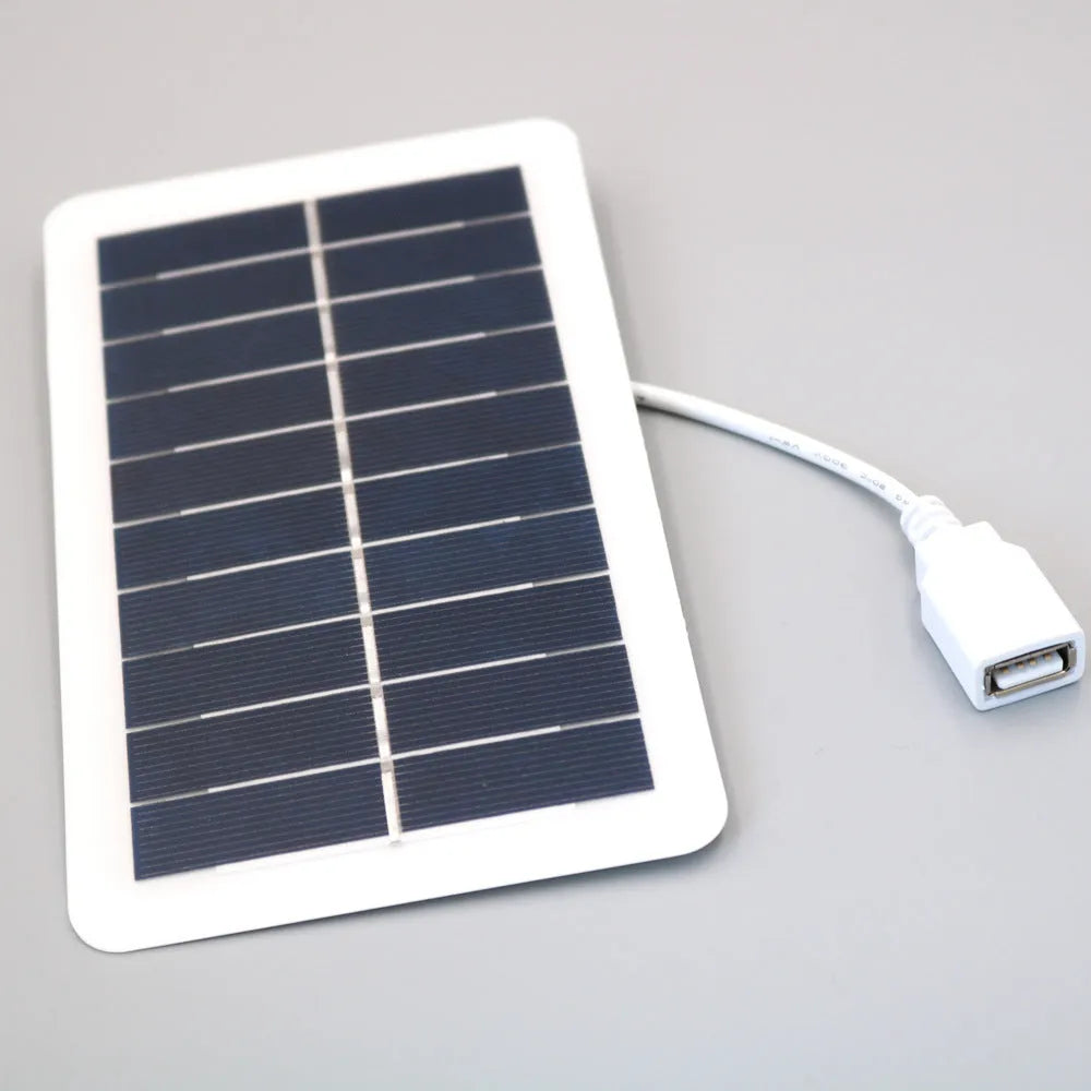 Black portable solar panel charger with USB port for mobile phones on a textured surface.