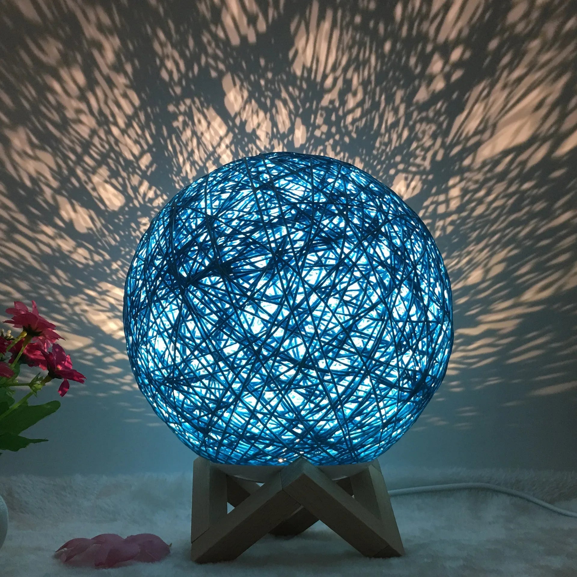 Rattan ball table lamp with woven shade and warm LED lighting on wooden surface
