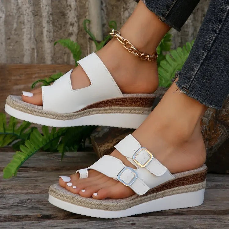 White patent leather women's wedge sandals with peep toe and woven detail on a rubber sole.