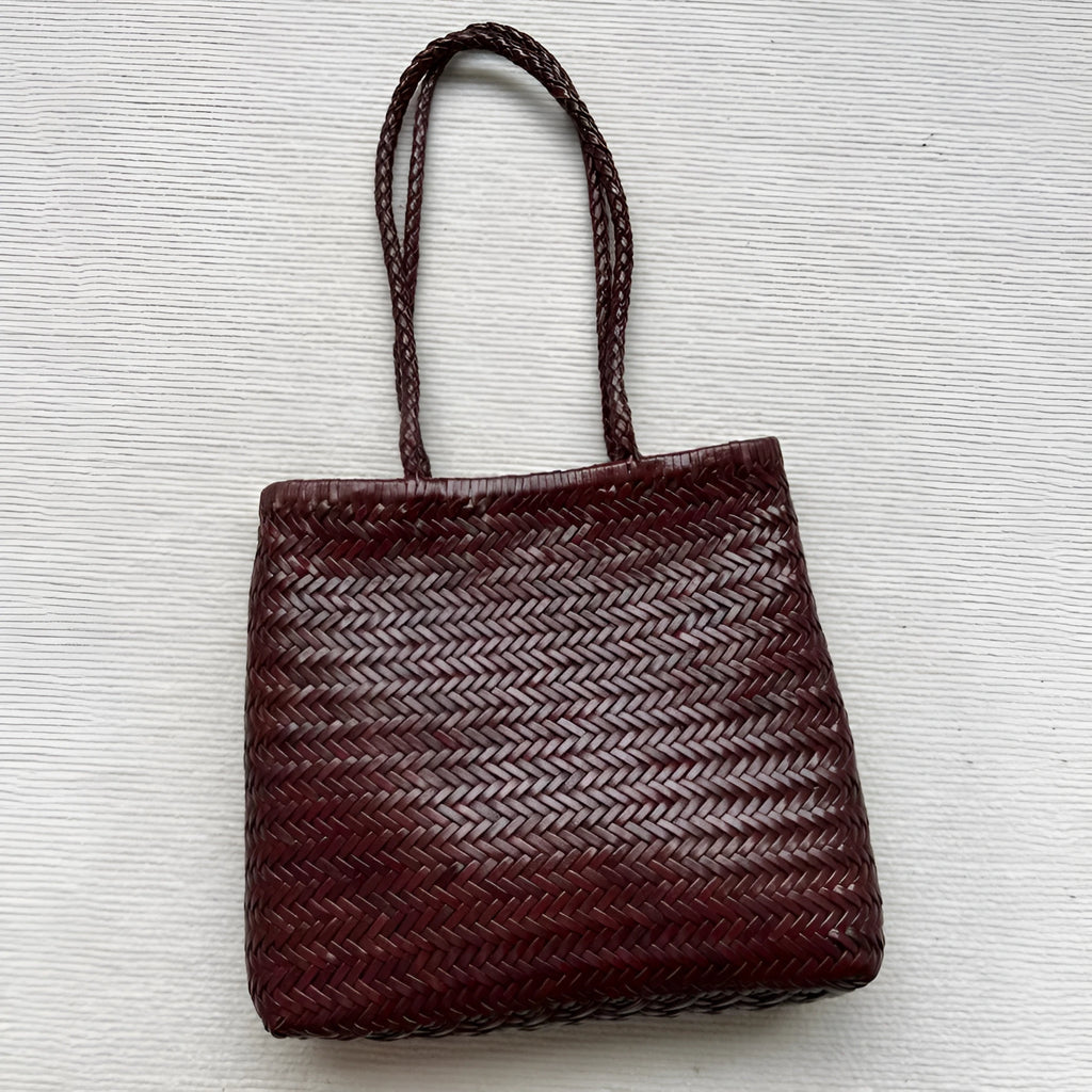 Brown vintage woven leather tote bag with a three-dimensional front pocket.