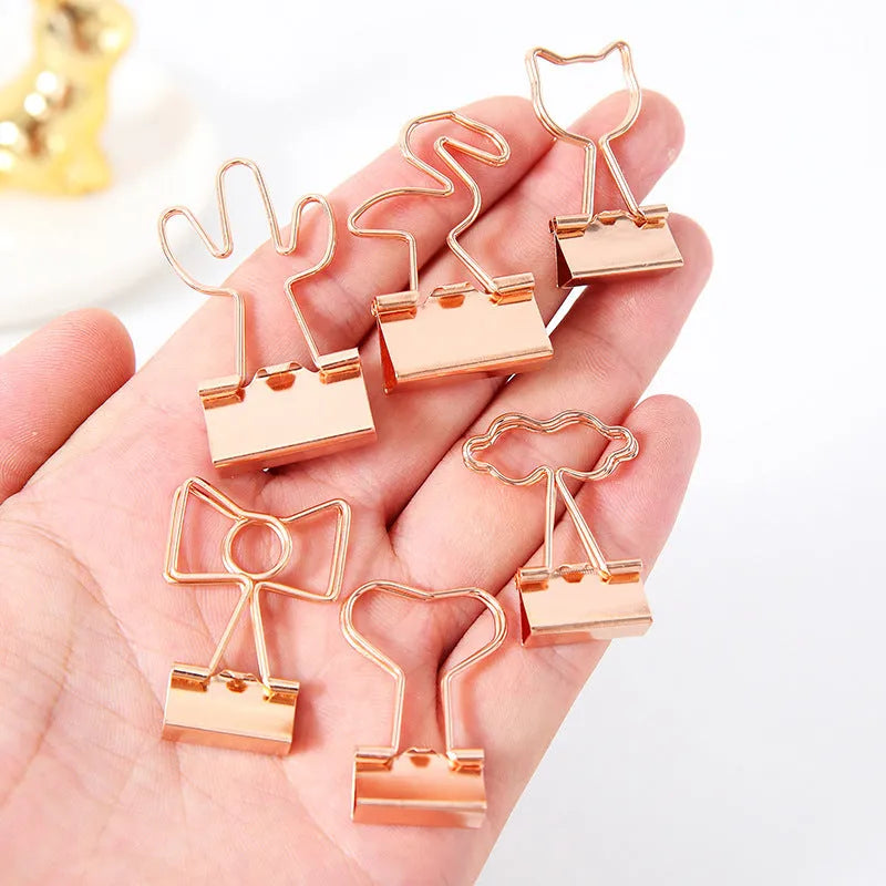Gold-coloured long tail metal clip with a choice of flamingo, love, clouds, cat, cactus, or bow decorative design.