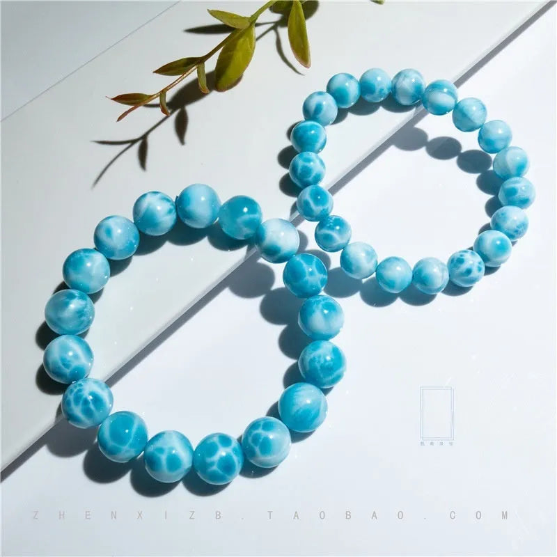 Blue handmade Bodhi bead bracelet with natural crystal and sea-pattern stone on a wrist.