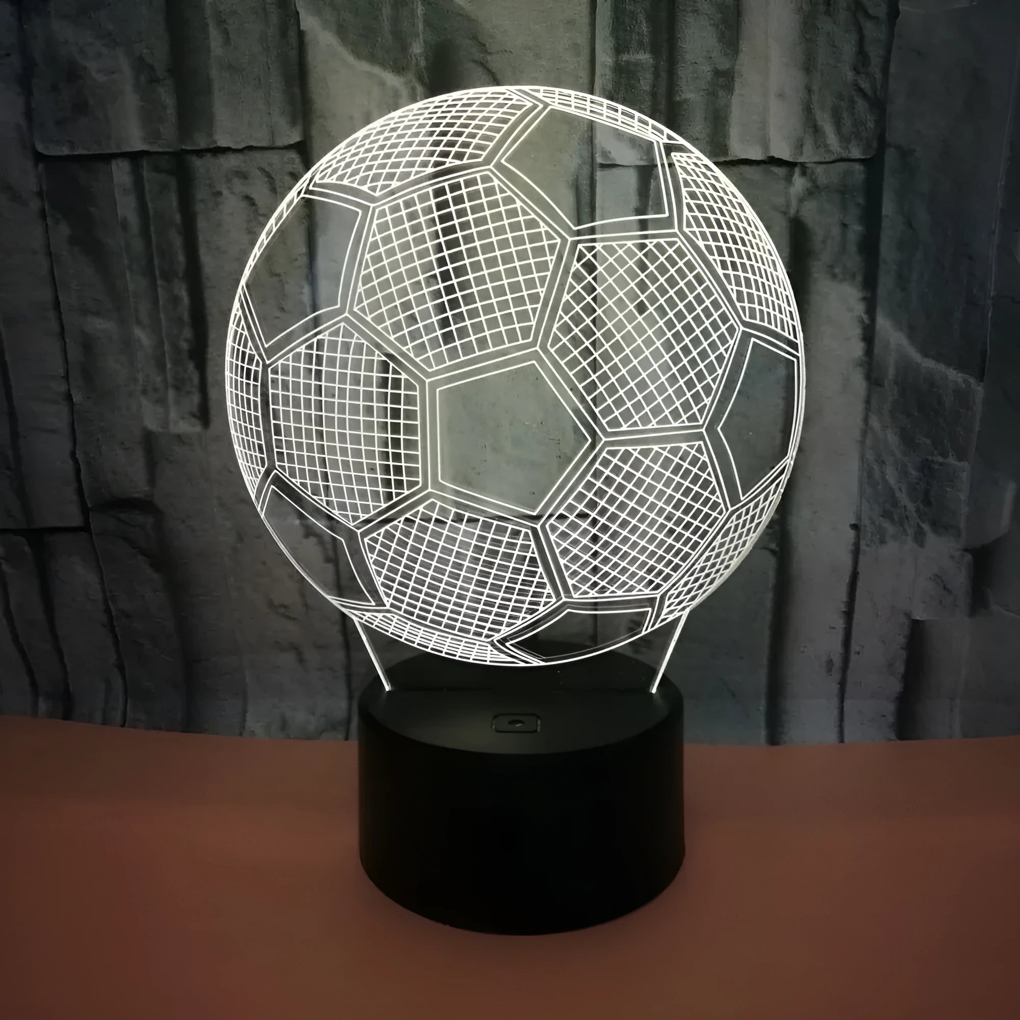 3D football-shaped LED night light on a black base showing multi-colour gradient illumination.