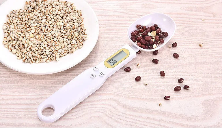 Black electronic measuring spoon scale on a kitchen counter showing digital display.