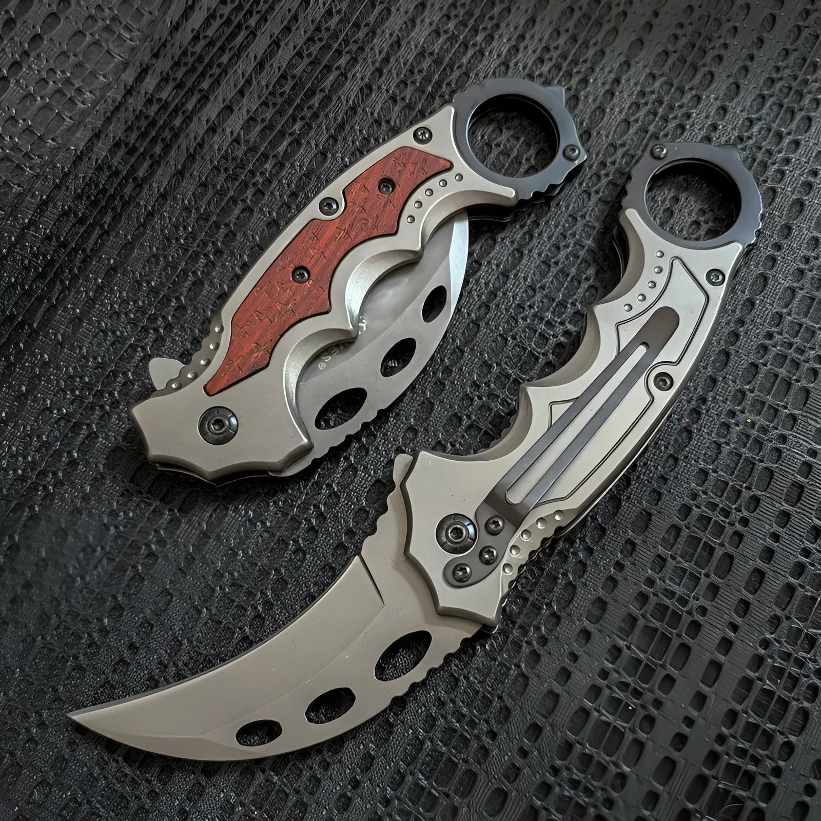 Folding claw knife with grey titanium blade and sour branch wood handle on a surface