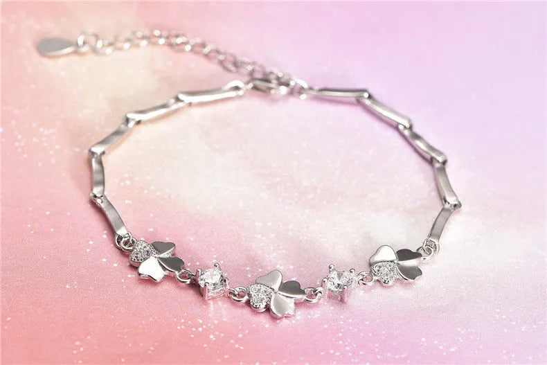 Silver four-leaf clover bracelet with adjustable chain on white background