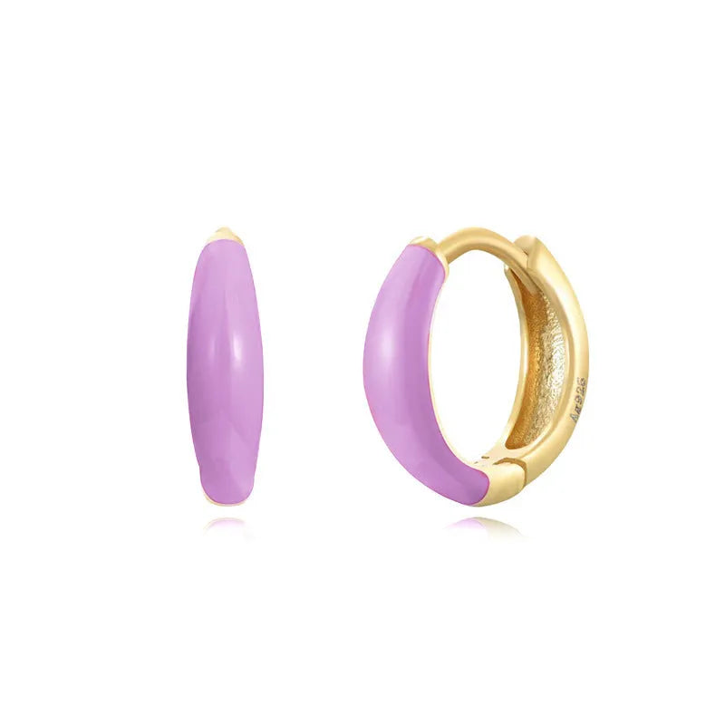 A pair of curved U-shaped drop earrings with a glossy light green oval and ring geometric design on copper wire.