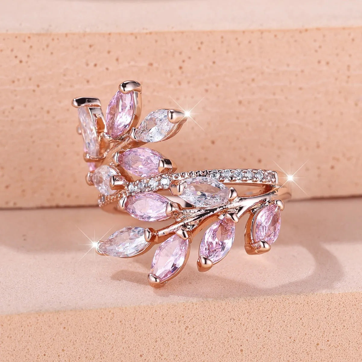 Adjustable copper leaf fashion ring with a central zircon stone on a model's hand, showing rose gold and platinum colour variants.