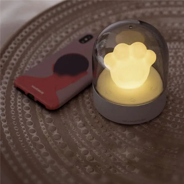 Grey cat paw shaped USB rechargeable musical night light on a wooden desk