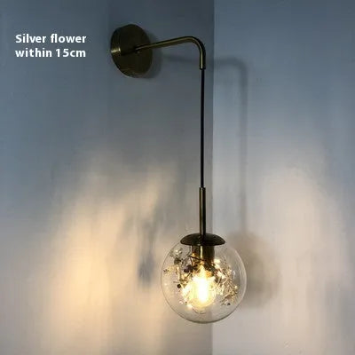 Modern creative wall-mounted bedside lamp with a golden flower glass shade and warm LED light.