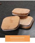 Square glass storage jar for coffee beans with wooden spoon on kitchen counter, clear body shows contents