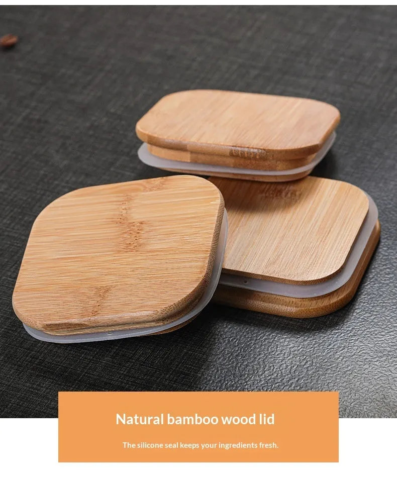 Square glass storage jar for coffee beans with wooden spoon on kitchen counter, clear body shows contents