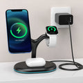 Black round wireless charging station with iPhone attached magnetically, Apple Watch on puck, and AirPods case on Qi spot.