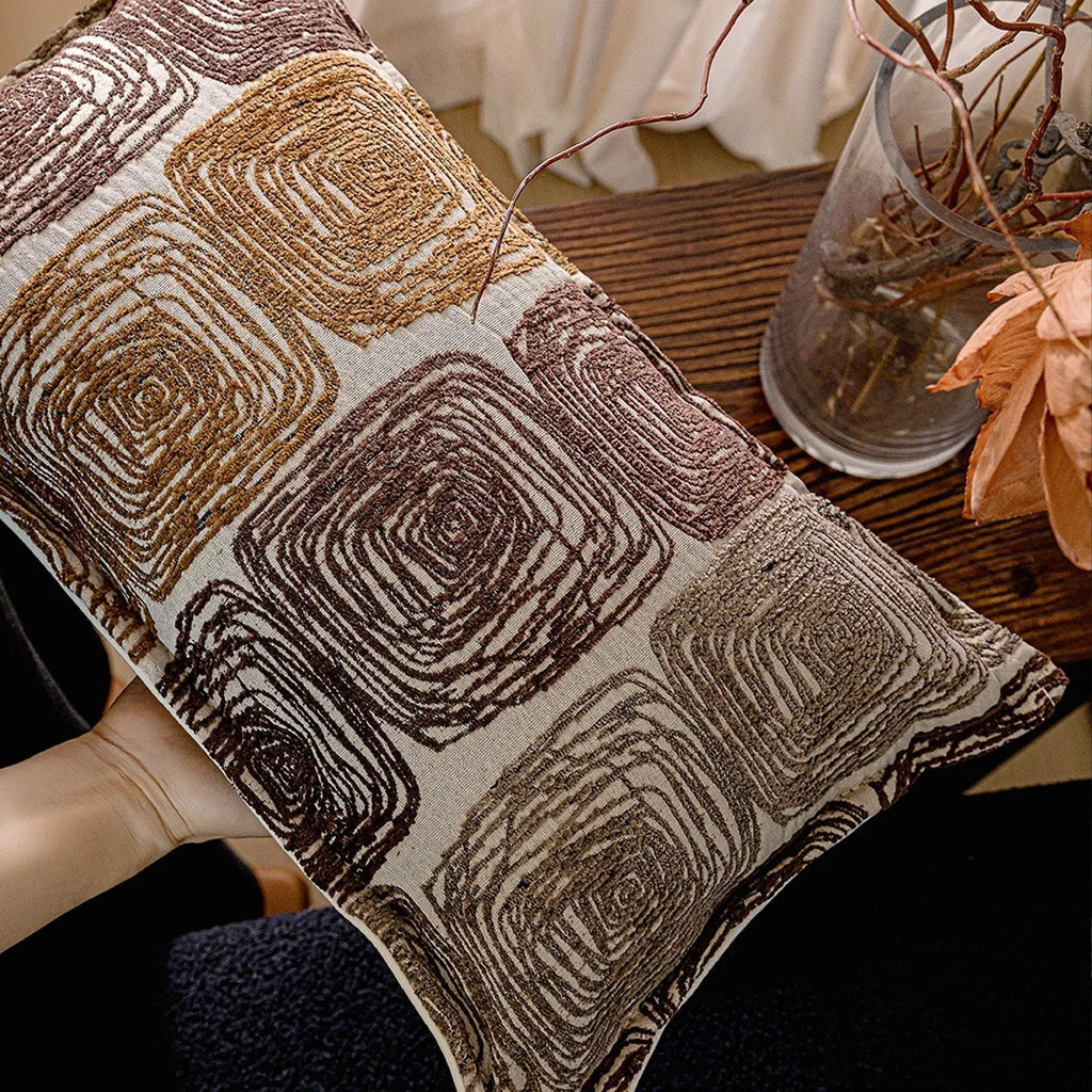 Cream and coffee coloured abstract coil pattern square and waist pillow covers on a sofa.